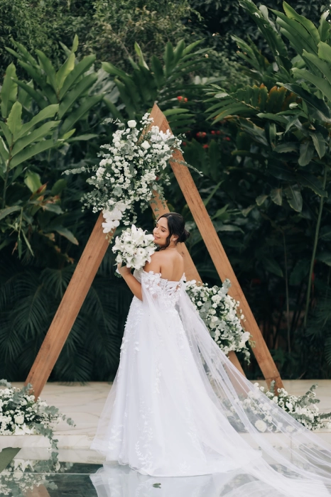 Noiva com vestido de tule bordado sob arco floral no jardim